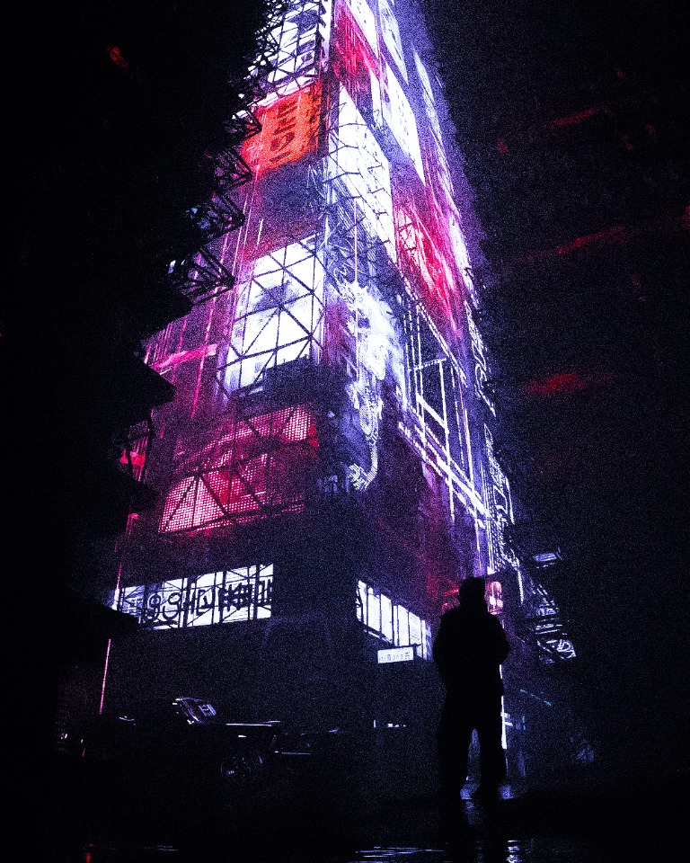 A person standing in front of a neon-lit city tower