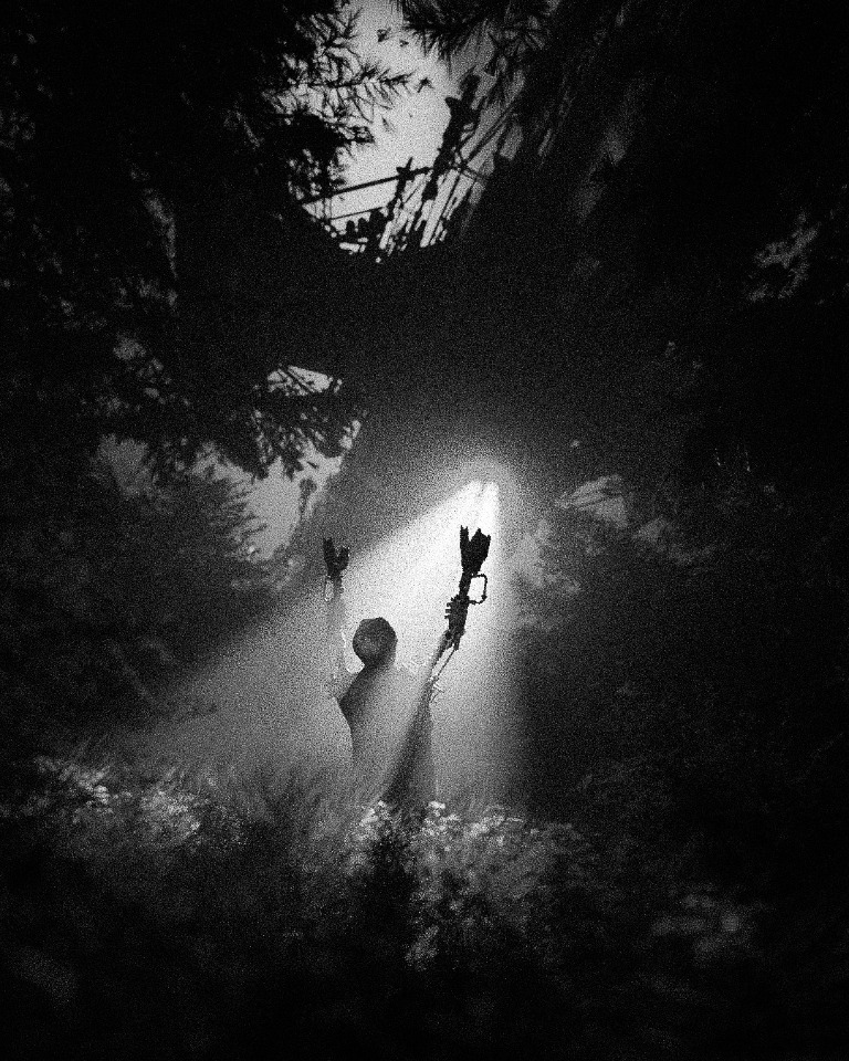 A silhouetted figure beneath the light between the trees